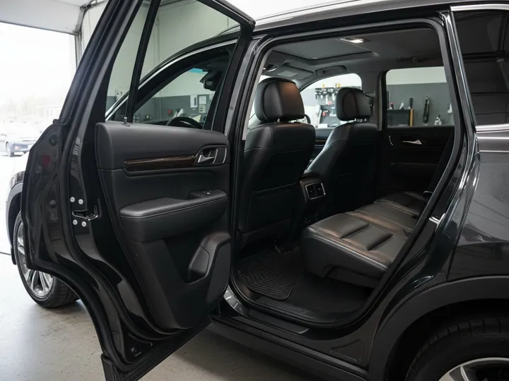 Clean black leather back seats and vacuumed floor mats seen through the open rear door of an SUV